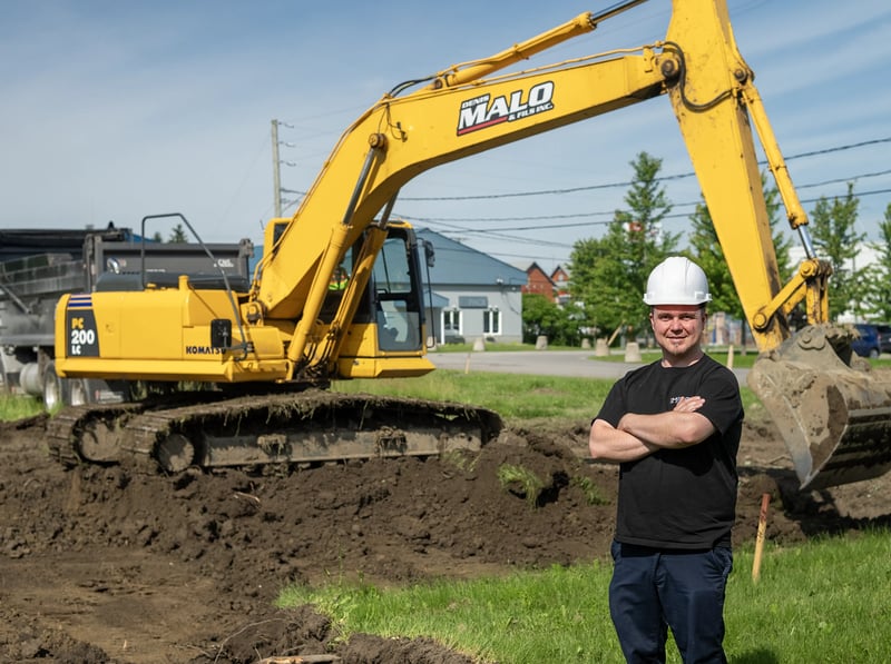 Michael Persechino, Director de Planta de IMPACK, de pie frente a una excavadora en la obra de construcción de las nuevas instalaciones de la empresa, junto a su sede.