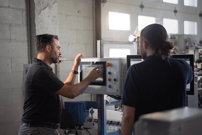Fred, responsabile dell'automazione di IMPACK, attiva i comandi sullo schermo di GenieCut HMI mentre Cédric è impegnato durante il collaudo della piattaforma di automazione presso lo stabilimento di produzione di IMPACK.