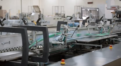 Carton blanks are being folded as they pass through the folder-gluer at high speeds